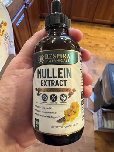 Hand holding a bottle of Respira Botanicals Mullein Extract in a kitchen setting.